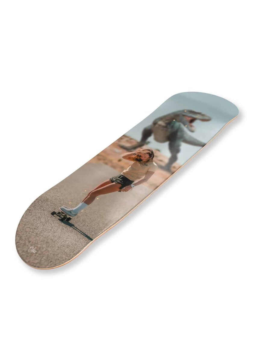 Planche de skateboard / skate art "Hurry" représentant une femme en skateboard poursuivie par un dinosaure
